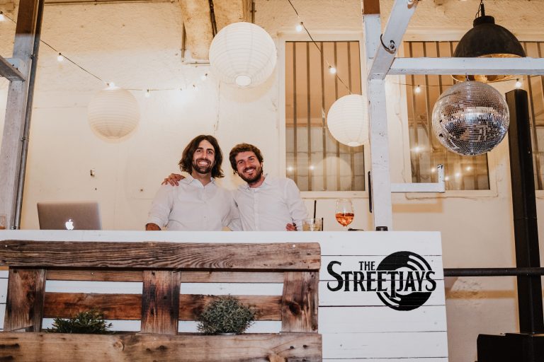 Das DJ-Duo The StreetJays posieren hinter dem DJ-Pult auf einer Hochzeit in Köln.